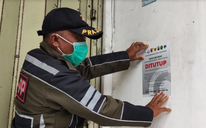 Petugas Satpol PP Kota Kediri saat menempelkan stiker pengumuman.