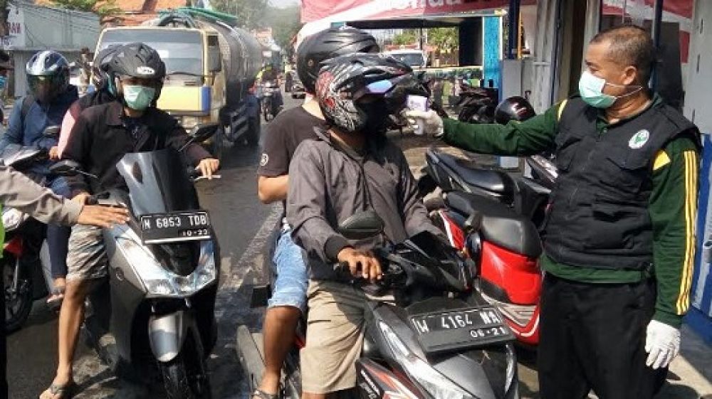 Pemeriksaan suhu tubuh pengendara motor yang melintasi check point di Porong, Sidoarjo, kemarin.