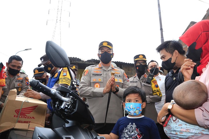 Sambil menggendong anaknya, Wahyu menerima motor dari Jokowi yang diserahkan langsung oleh Kapolrestabes Surabaya, Kombes Akhmad Yusep Gunawan, Senin (14/2/2022). Sp/Amin