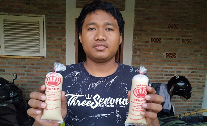 Jarifin memamerkan susu kedelainya di depan rumah produksi. SP