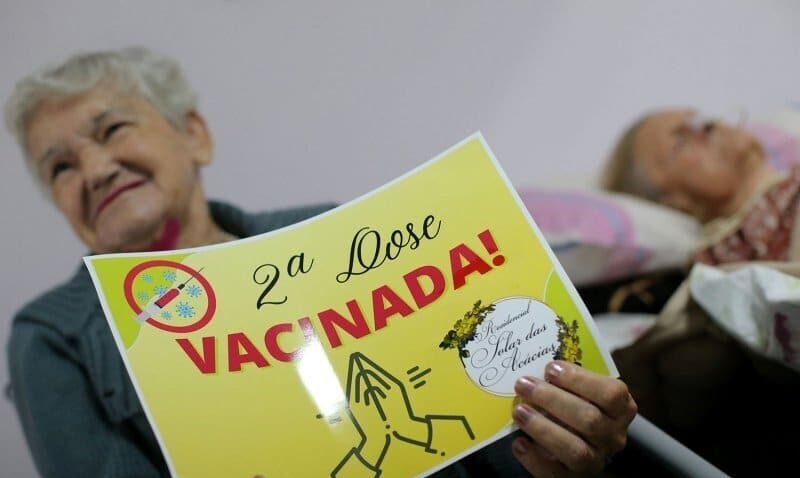 Seorang warga lanjut usia memegang kertas bertuliskan "Dosis kedua. Vaksinasi!". SP/ BRZ