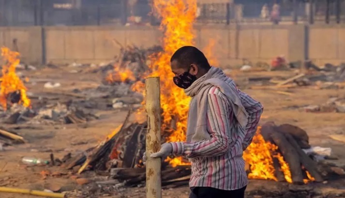  Seorang pria India tampak sibuk membakar jenazah pasien Covid 19 yang tak terkendali jumlahnya.