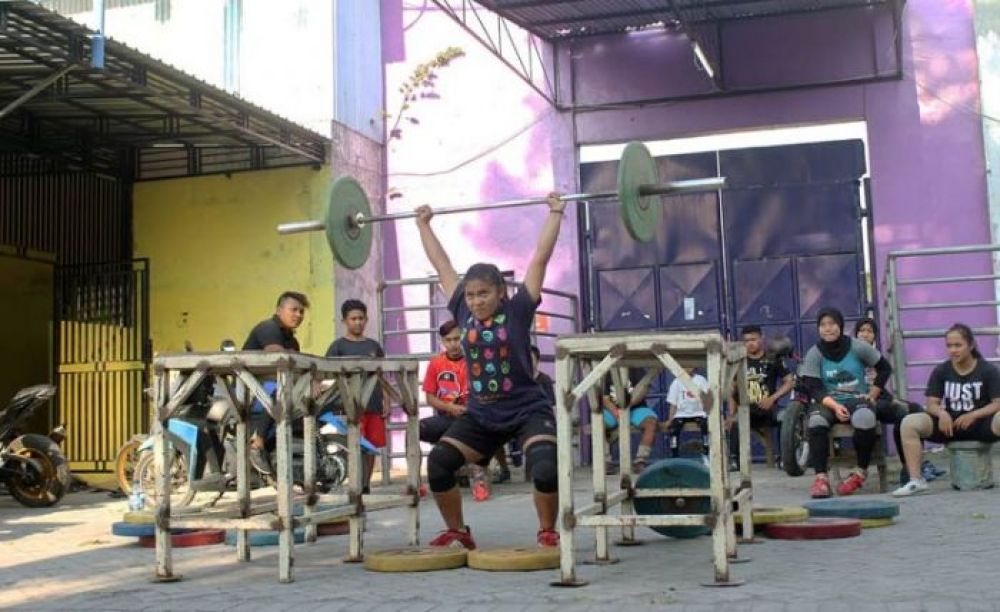 Salah satu atlet perempuan saat mencoba angkat beban disaksikan para atlet lainnya.bo