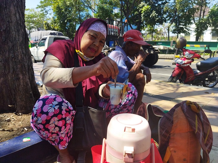 Bu Kosnah alias Bu Titi saat membuat kopi susu bagi pelanggan. SP/Semmy Mantolas