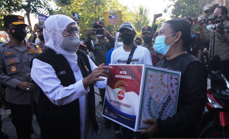 Gubernur Jatim Khofifah Indar Parawansa (tengah) didampingi Kapolda Jatim Irjen Pol Nico Afinta (kiri) membagian paket bantuan kepada warga terdampak PPKM darurat di kawasan Bulak Banteng di Surabaya, Minggu (18/7/2021) sore