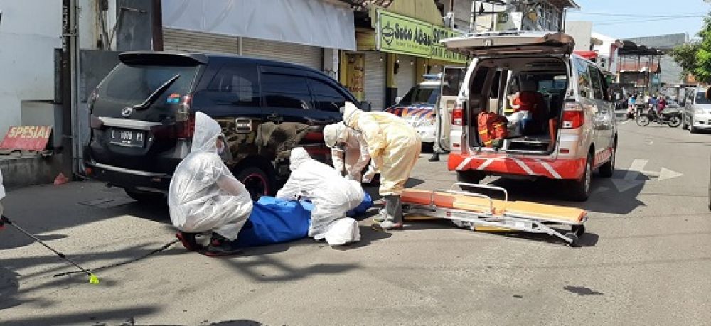 Petugas dengan mengenakan pakaian pelindung lengkap mengevakuasi jenazah wanita yang tewas di dalam mobil taksi online. (SP/jimmy)