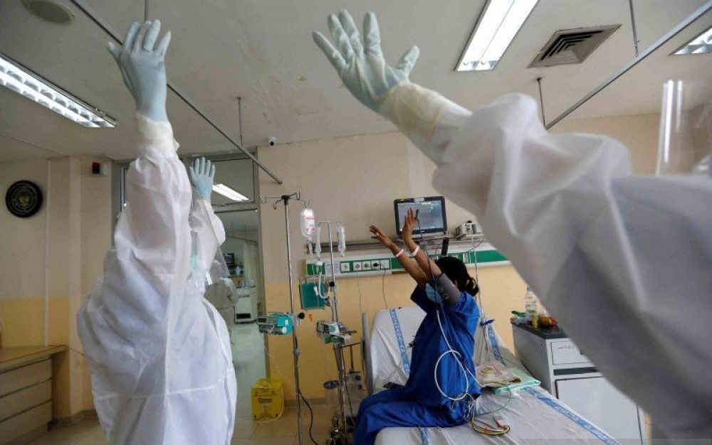 Ilustrasi - Tenaga medis dengan alat dan pakaian pelindung membantu pasien melakukan peregangan tubuh.SP/ant