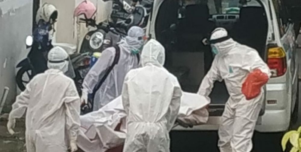 Petugas dengan menggunakan APD mengevakuasi jenazah korban yang telah membusuk didalam rumahnya.