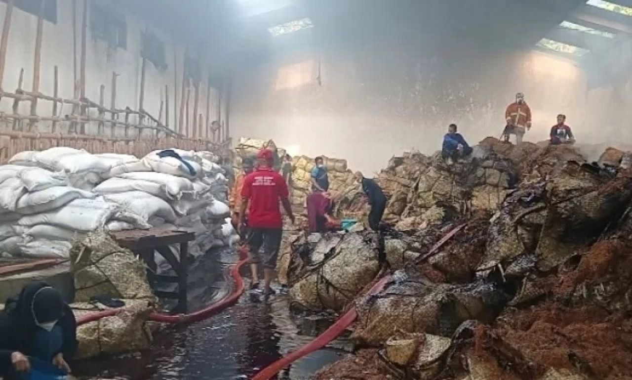 Petugas pemadam kebakaran saat melakukan pembasahan di gudang tembakau di Keluarahan Lawangan Daya, Pamekasan.