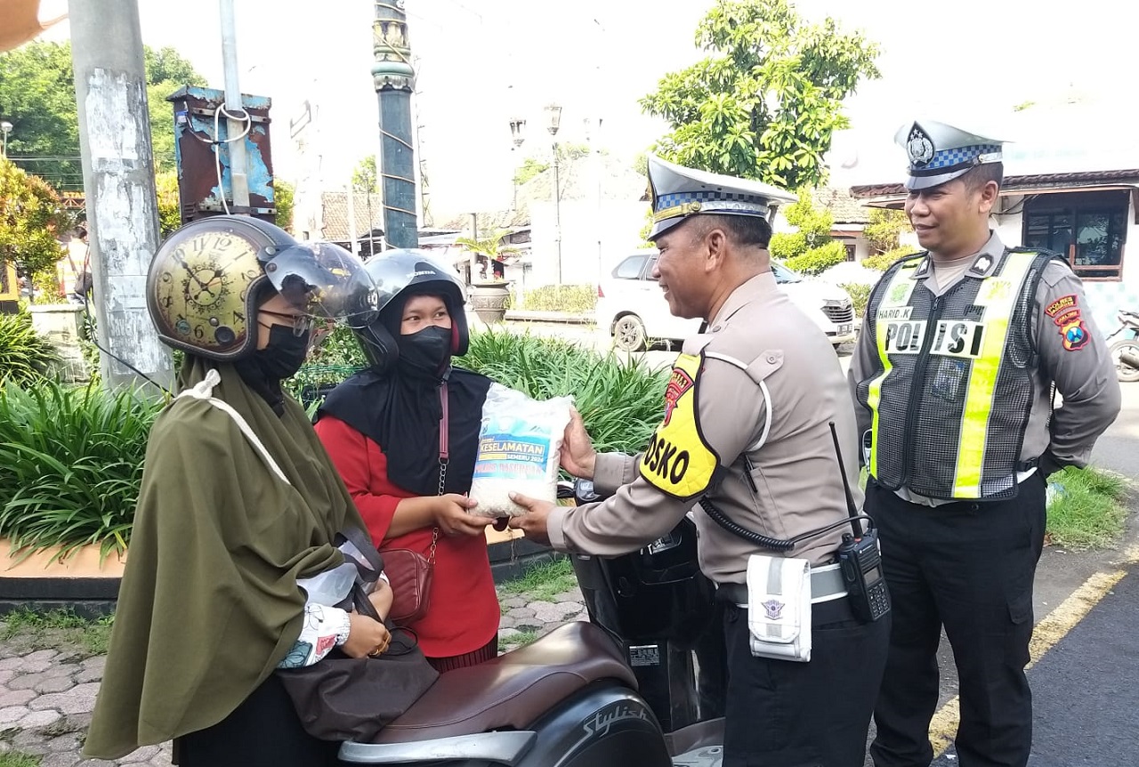 Salah satu anggota satlantas polres Pasuruan saat memberikan surprise berupa beras kepada  pengguna jalan. SP/ HIKMAH