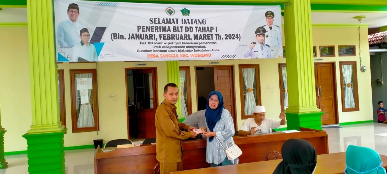 Kades Tanggul, Syaiful Akhmadi, saat menyerahkan uang bantuan kepada salah satu warga penerima. SP/JUM