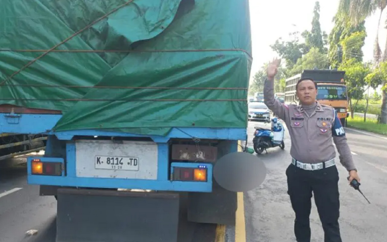 Petugas mencoba mengatur arus lalu lintas sembari menunggu evakuasi korban meninggal akibat kecelakaan motor dengan truk gandeng yang terjadi di Jalan Jaksa Agung Suprapto, Lamongan, Senin (29/04/2024). SP/ Ipda Hadi via WA SS