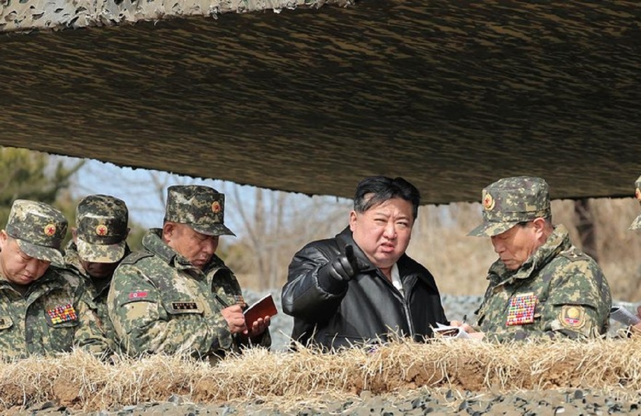 Kim Jong-Un memakai jaket kulit berwarna hitam sedang berbicara dengan tentara bersenjata lengkap berseragam kamuflase yang sedang mengawasi latihan penembakan dan memeriksa persenjataan. SP/ Reuters