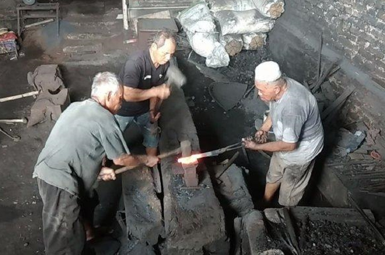 Pemilik Pande Besi Mohari sedang memanggang lempengan besi di atas bara besi, Desa Sewulan, Kecamatan Dagangan, Kabupaten Madiun. SP/ MDN