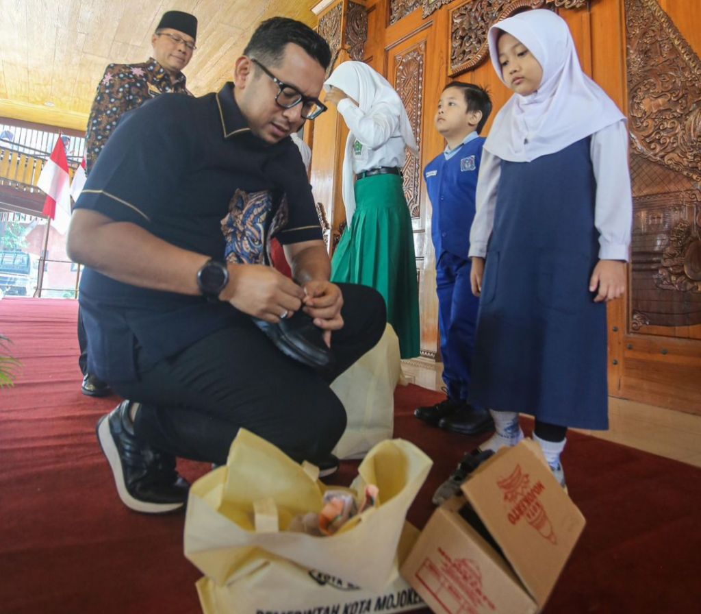Pj Wali Kota Moiokerto Moh. Ali Kuncoro saat menyerahkan perlengkapan aekolah gratis kepada siswa didik baru.