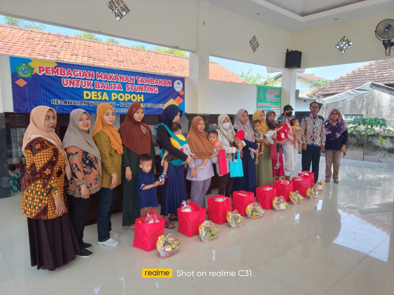 Kades Popoh, Sugini, saat foto bersama ibu dan balita penerima bantuan paket makanan tambahan. SP/JUM