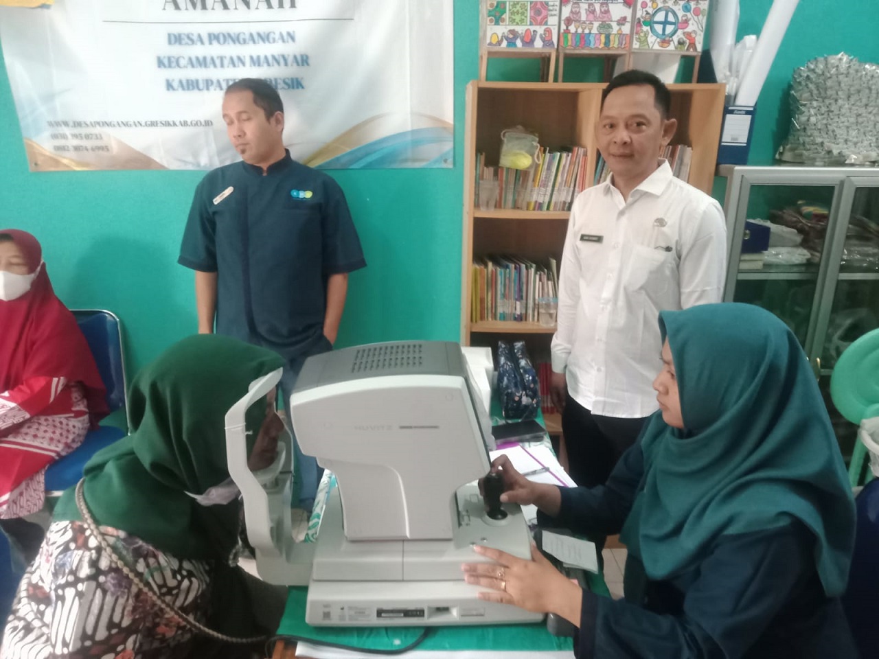 Kepala Desa Pongangan Aang Chunaifi mendampingi warganya saat pemeriksaan mata di balai desa setempat, Rabu (21/08/2024). SP/ M. Aidid