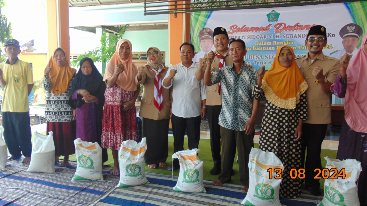 Plt Bupati Sidoarjo, H. Subandi, SH, M,Kn saat foto bersama Kades Segodobancang, Slamet Rianto dan warga penerima bansos beras. SP/JUM