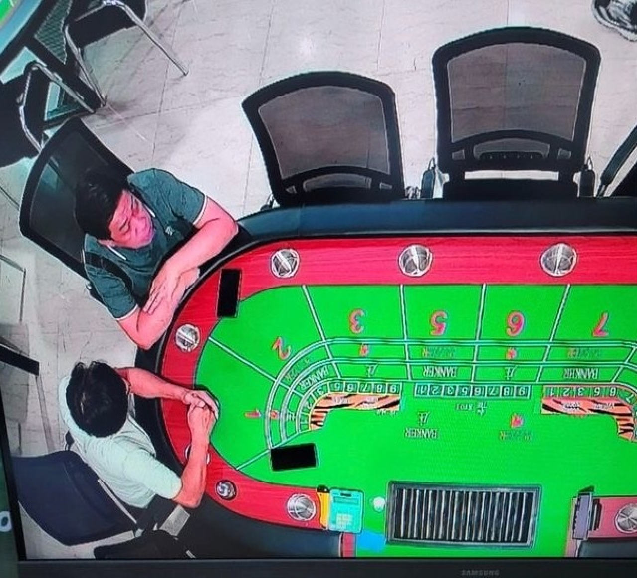 Edy Medan, berkaos hijau gelap duduk di meja Baccarat. Foto ini dikirim Alung, ke redaksi Surabaya Pagi, melalui no HP 0813‑3327‑xxxx. Saat datang ke redaksi Surabaya Pagi, wajahnya tidak berubah.