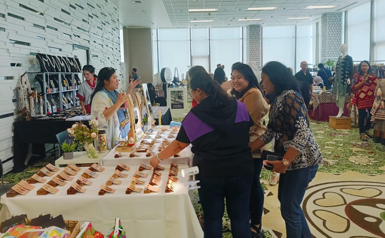 Zara (kiri), pemilik UMKM Hexagon asal Jakarta sedang menjelaskan produk unggulannya yaitu aksesoris dengan pewarna dari make up kadaluwarsa kepada calon pembeli. Foto/Humas PLN