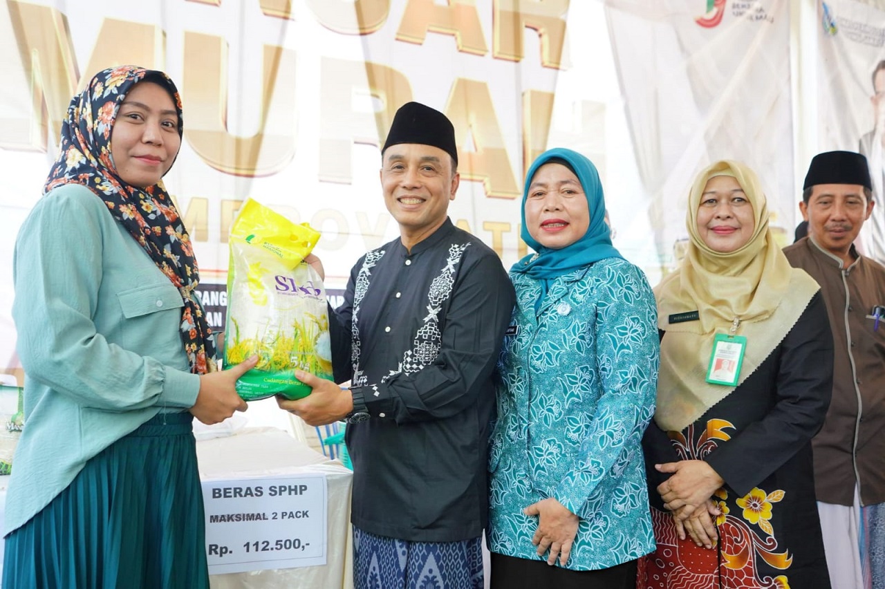 Pj Wali kota Probolinggo M. Taufik Kurniawan secara simbolis menyerahkan beras kepada pembeli yang membeli beras di pasar murah di Kecamatan Kanigaran. SP/ PRB