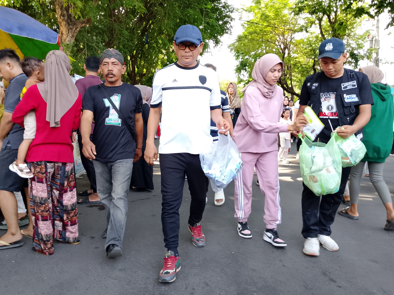 Cabup Abdul Ghofur bersama istrinya menenteng tas kresek usai memungut sampah satu persatu mengelilingi alun-alun Lamongan, Minggu (17/11/2024). FOTO:SP/MUHAJIRIN