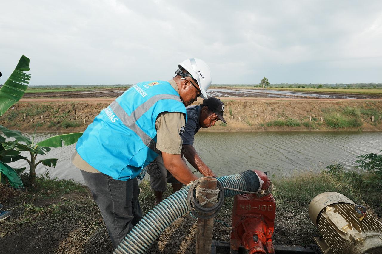Petugas PLN bersama salah satu petani menyalakan pompa air bertenaga listrik untuk mengairi sawah di lahan percontohan Kawasan Food Estate di Kampung Telaga Sari, Merauke. Foto/Humas PLN