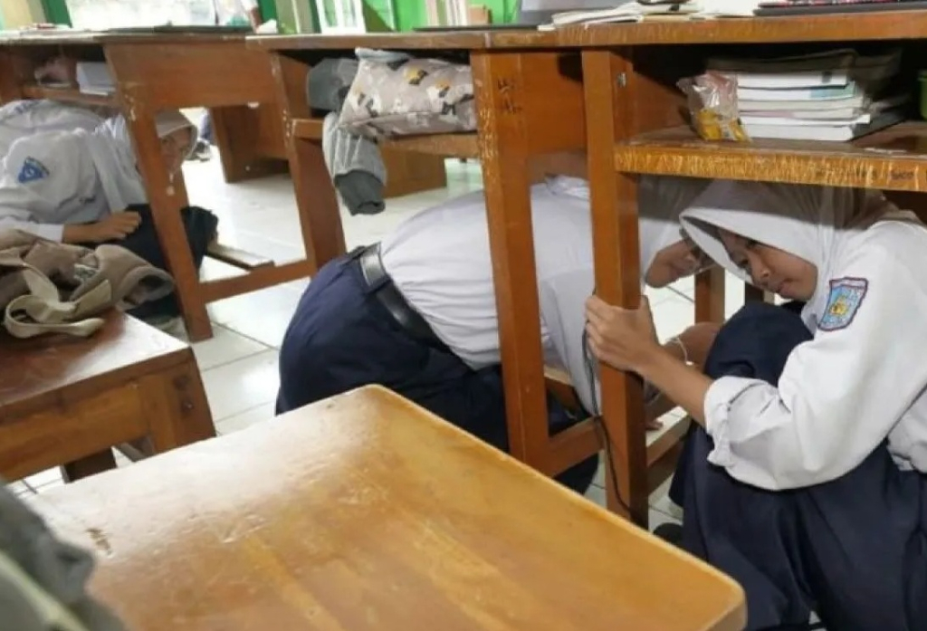Sejumlah siswa berlindung di bawah meja saat mengikuti kegiatan simulasi penanganan gempa bumi yang digelar BPBD Kota Madiun. SP/ MDN