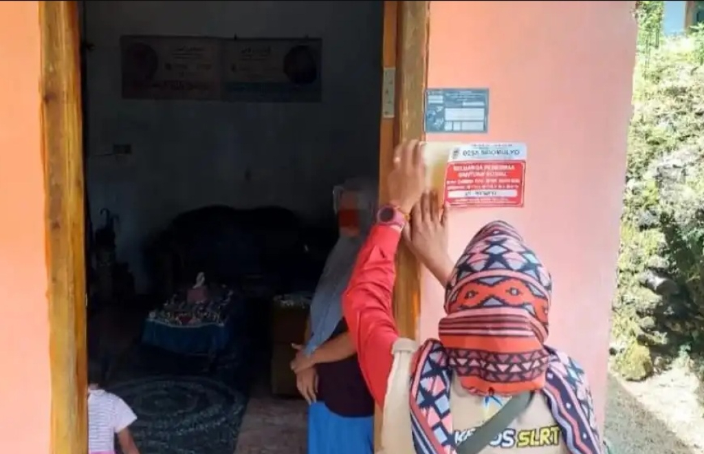 Petugas Dinas Sosial Kabupaten Pacitan, Jawa Timur bersama pemerintah desa memasang label rumah keluarga penerima manfaat (KPM). SP/ PCT