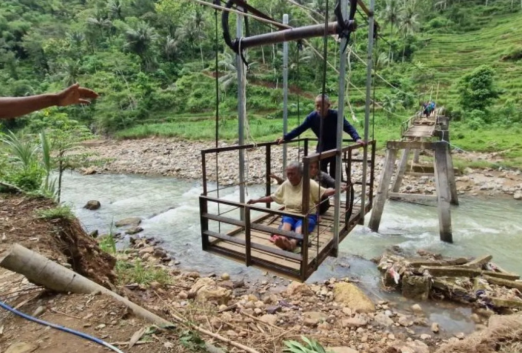 Sejumlah pelajar dan warga melintasi jembatan gantung swadaya yang dibangun sebagai akses darurat penghubung Kabupaten Ponorogo dan Kabupaten Trenggalek di Dusun Purworejo. SP/ PNG