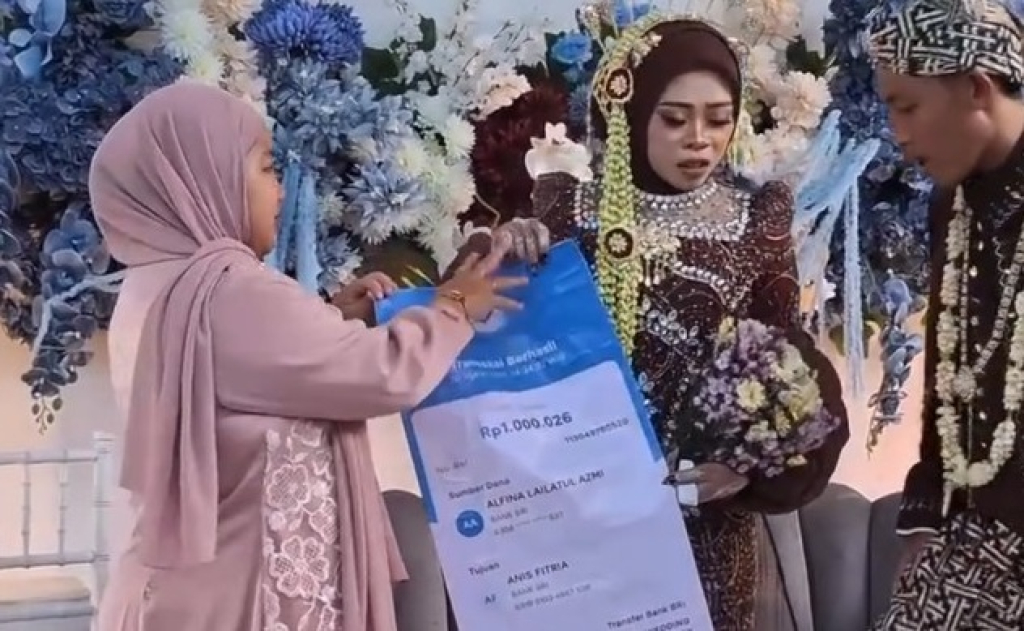 Tangkapan layar video. Sang tamu perempuan itu membawa 'amplop' berupa banner untuk pengantin di Lamongan. SP/ LMG
