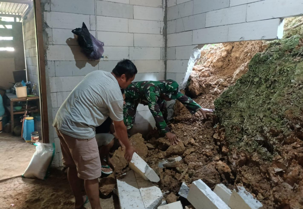 Petugas Koramil dibantu warga saat mengevakuasi matrial longsor yang menimpa rumah warga di Kecamatan Slahung. 