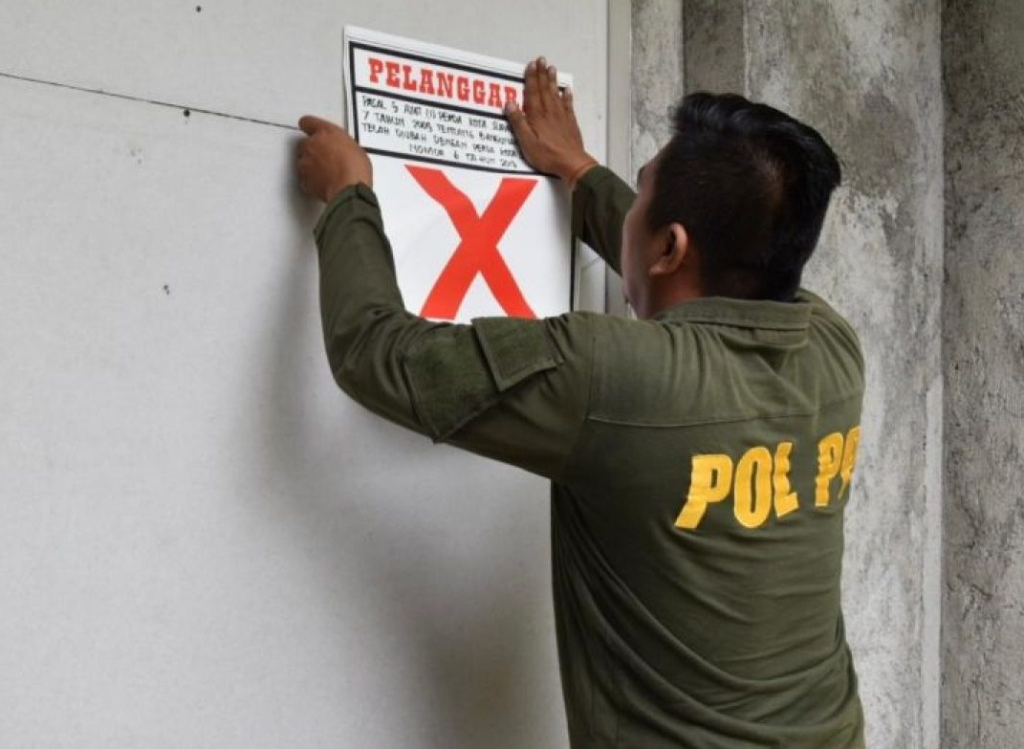 Petugas Satpol PP Surabaya memasang stiker pelanggaran di Kota Surabaya. SP/Foto:Pemkot Surabaya