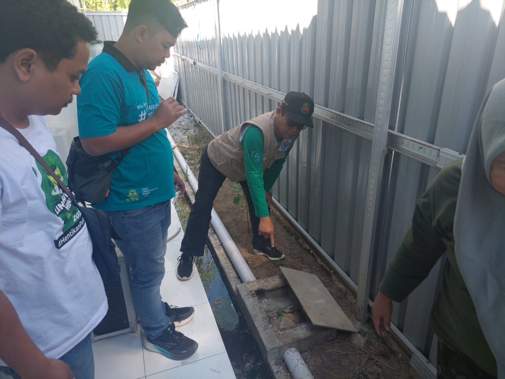 Petugas DLH menunjukkan aliran lindi berbau mengaliri drainase SPPG Grogol yang diduga juga mengalir ke drainase di warga. 