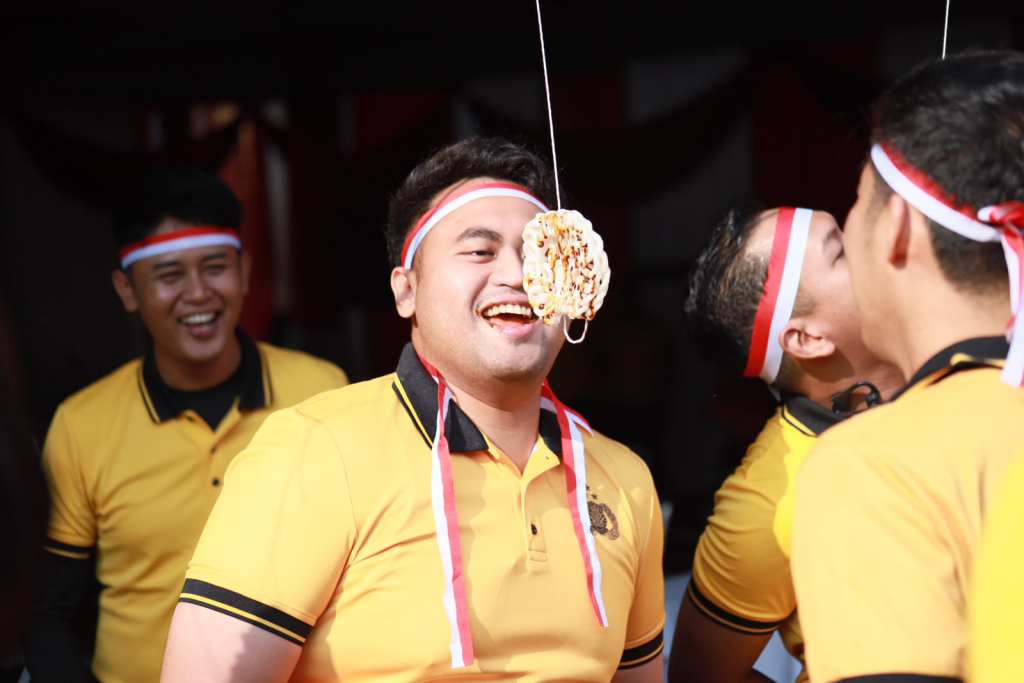 Kapolsek Gresik Kota AKP Kevin Ramadhan menjadi salah satu peserta lomba makan kerupuk menyambut HUT Proklamasi ke-81 RI di halaman Mapolres Gresik. SP/ MAIDID