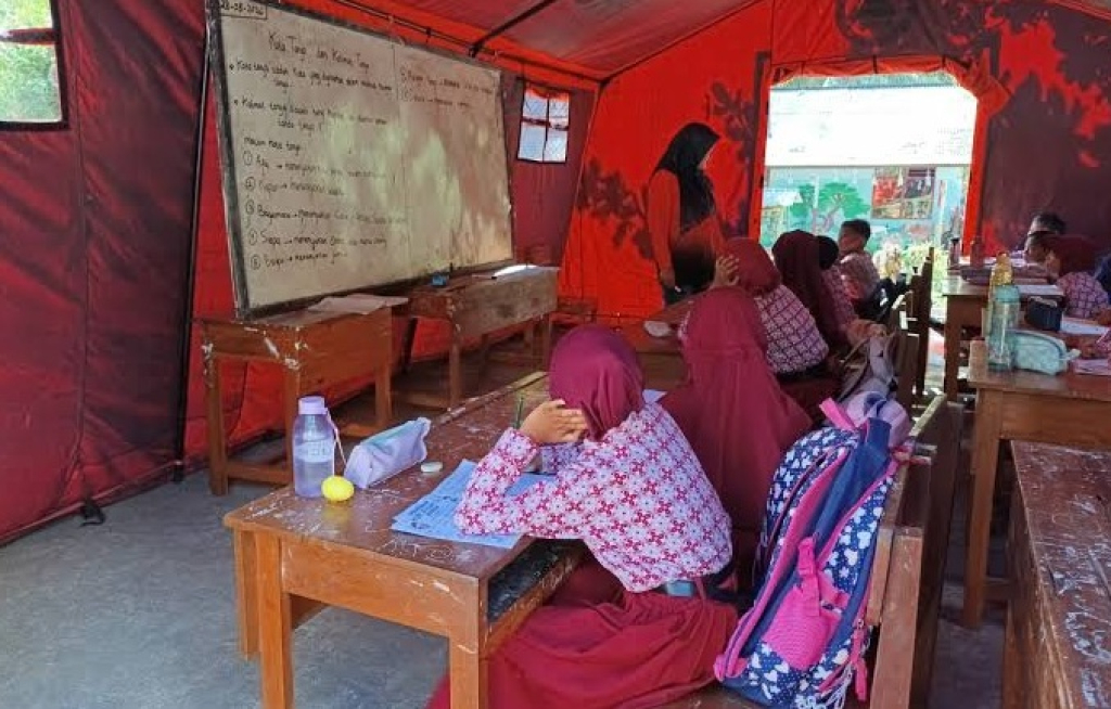 Guru mengajar siswa kelas II di ruang kelas darurat memanfaatkan tenda bantuan BPBD di SDN 3 Wonorejo, Tulungagung. SP/ TLG