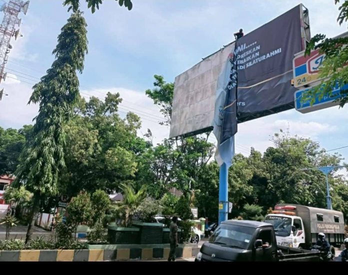 Petugas Satpol PP menurunkan banner permintaan maaf dari relawan HATI.