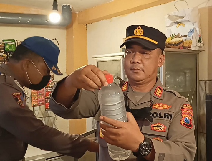 Kapolsek Manyar AKP Windu saat memeriksa botol miras di sebuah warung kopi. SP/Grs