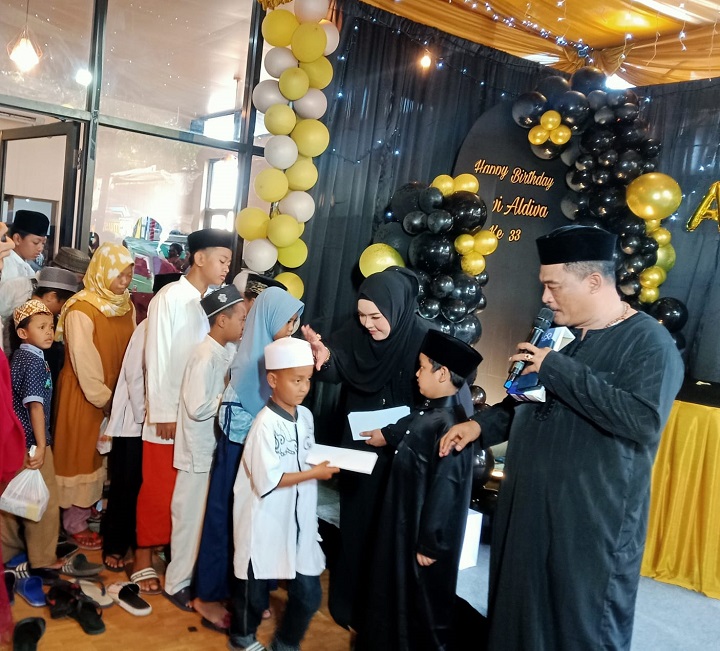 Pengusaha Sueb Abdullah dan istri saat membagikan sendiri santunan kepada anak yatim piatu yang diundang ke kafenya, Ahad (19/2). SP/Grs