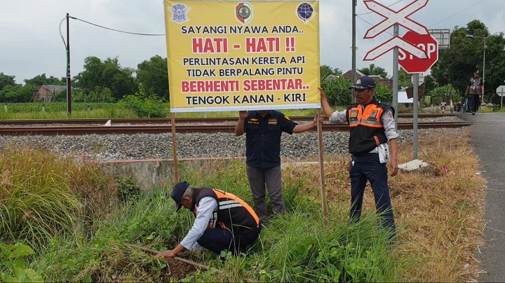 Petugas DPRKPP Kabupaten Mojokerto memasang papan imbauan di perlintasan tanpa palang pintu Desa Bicak, Kecamatan Trowulan. Dwi
