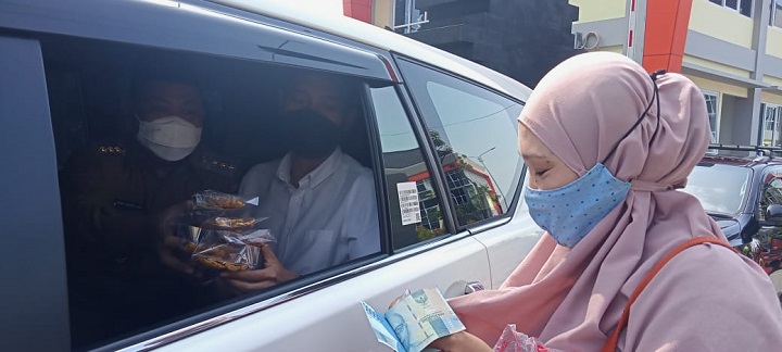 Hima saat menerima pembayaran  rempeyek dagangannya dari Gus Yani dari atas mobil. SP/M.AIDID