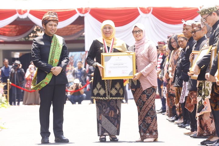 Gubernur  Jawa Timur, Hj Khofifah Indar Parawansa saat menyerahkan penghargaan kepada Bupati Blitar, Hj Rini Syarifah