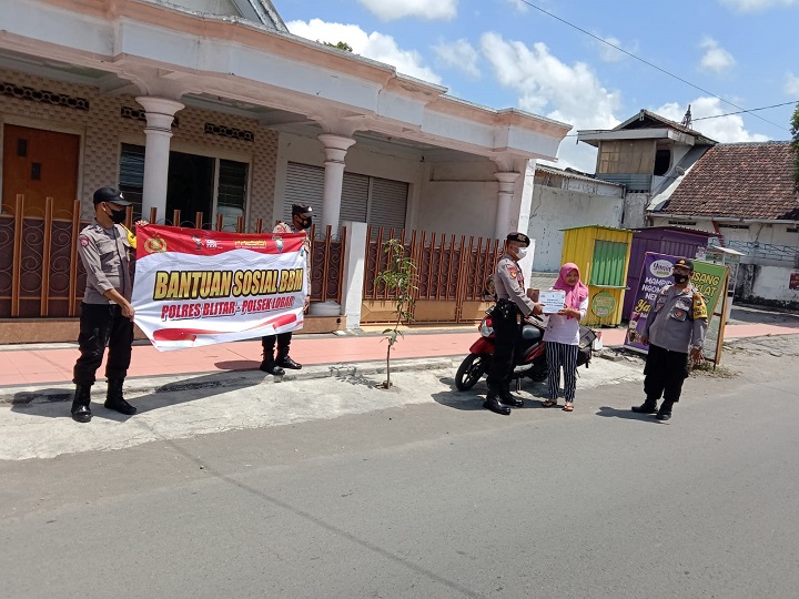 Polsek Lodaya Barat membagikan bantuan di Jalan Banteng blorok Desa Rejowinangun. SP/Hadi Lestariono