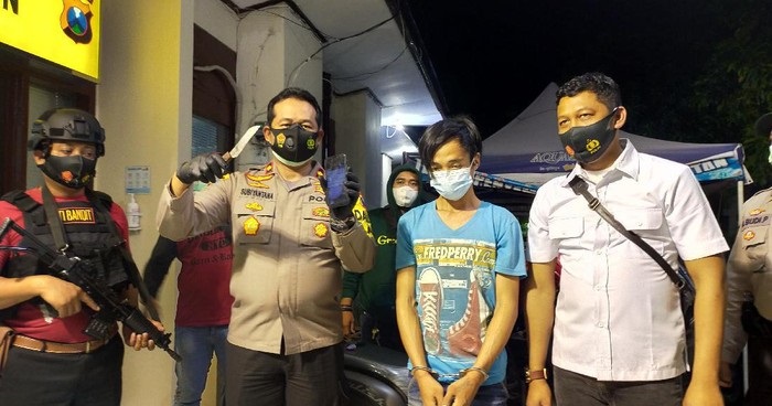 Polisi menunjukkan pelaku dan barang bukti sajam yang digunakan pelaku untuk membacok korban. 