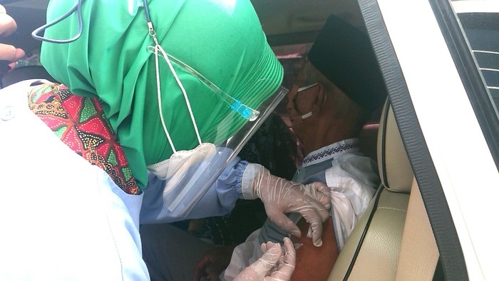 Petugas saat menyuntikkan vaksin covid-19 kepada seorang lansia secara drive thru. 