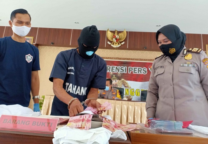 Tersangka pengganda uang menunjukkan barang bukti uang palsu saat rilis kasus di Polres Temanggung. 
