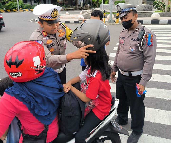 Petugas memberikan helm gratis kepada pengendara motor. SP/Hadi Lestariono