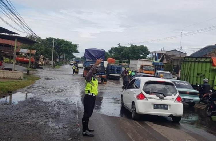 Petugas saat menertibkan lalin di Jalur pantura Pasuruan yang macetkan karena banjir. SP/ DECOM