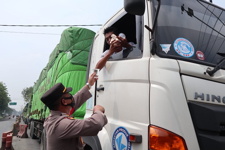 Petugas kepolisian membagikan nasi bungkus dan air mineral kepada sopir truk yang mengalami kemacetan di jalan Pantura Manyar, Gresik. SP/Grs