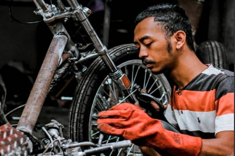 Alfian yang sedang mendandai motor lawas. SP/ SBY